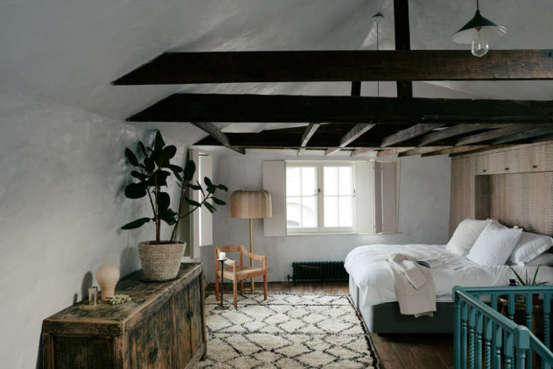 The bedroom is done with dark wooden beams, an antique sideboard and rather contemporary furniture and rugs