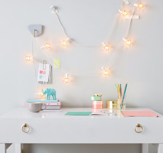 a chic small desk with pastel touches and cute lantern string lights over it