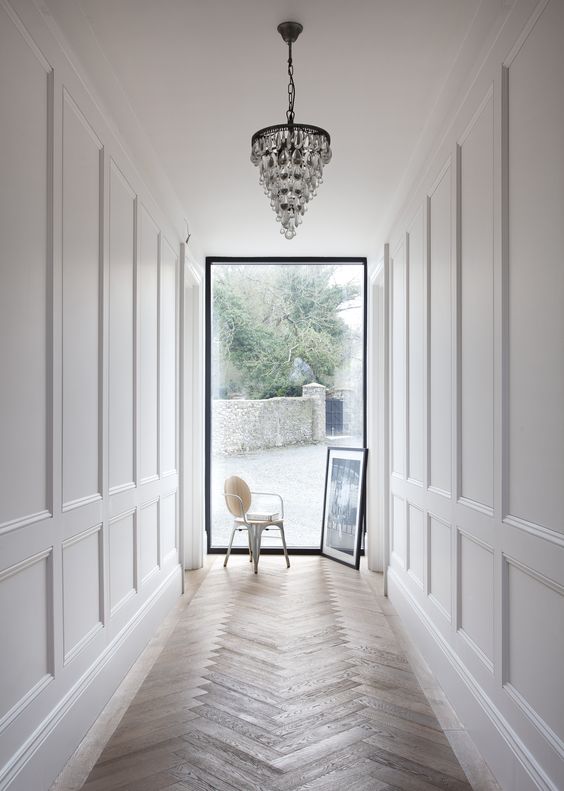 a entrance corridor with paneling and a glam chandelier will impress everyone
