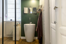 11 The bathroom is done with green and geometric wallpaper, wooden floors and a cool free-standing sink