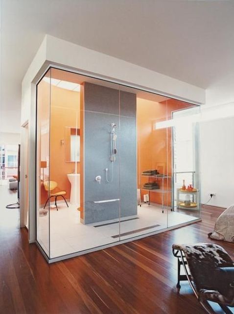A modern glass enclosed bathroom with orange and grey tiles right in the interior