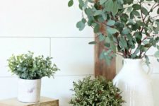 11 potted greenery and some green branches in a vase for a rustic or farmhouse mantel