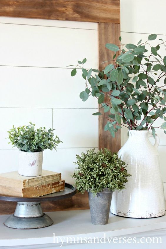 potted greenery and some green branches in a vase for a rustic or farmhouse mantel