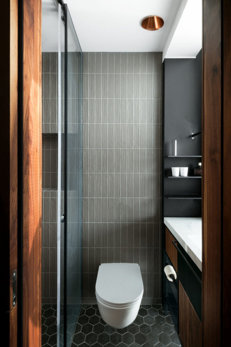 The bathroom is done with the shades of grey and warm-colored wood