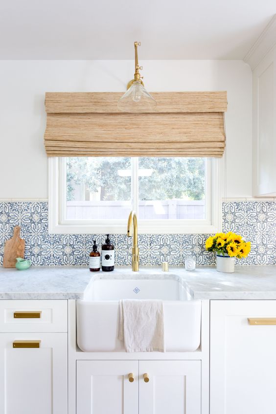 a neutral kitchen is spruced up with blue patterned tiles and brass touches