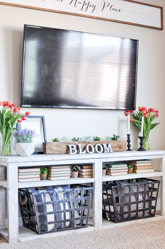a console table with potted greenery and tulips in vases plus some books