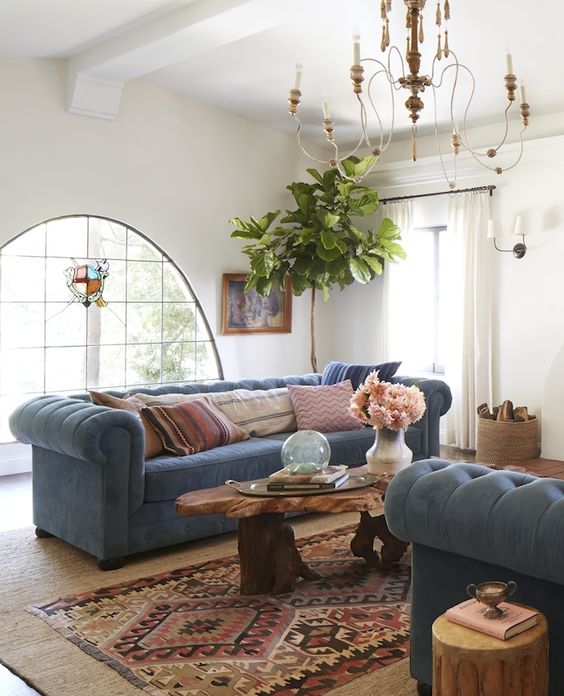 a boho rustic living room with two powder blue Chesterfield sofas that add a calming touch to the bold space