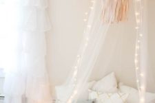 15 a sheer canopy with fabric pompoms and string lights is sure to make a girl’s bed welcoming