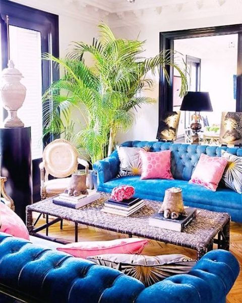 a bold art decor space with bright blue Chesterfield sofas and a woven coffee table