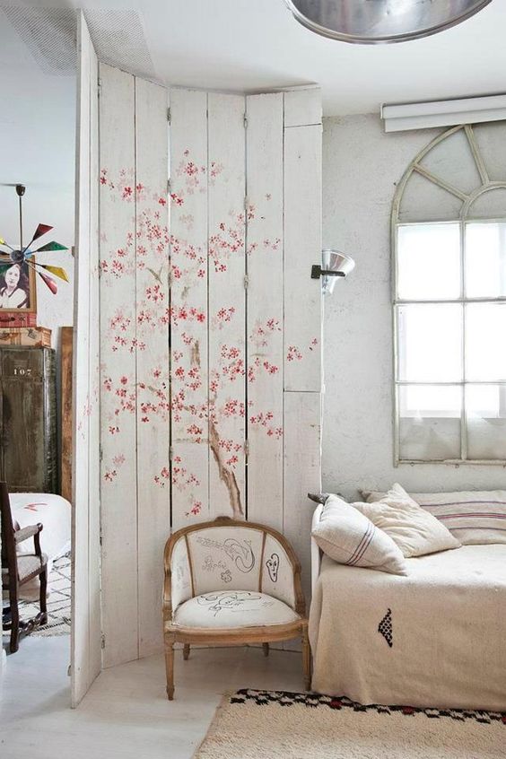 a whitewahsed pallet screen with tender cherry blooms to accent the bedroom