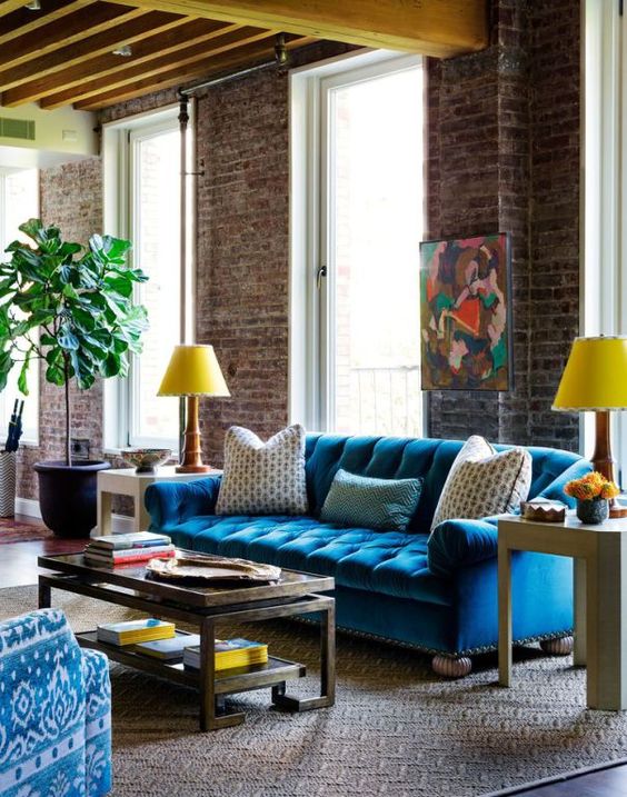 a colorful living room with industrial touches and a bold blue Chesterfield sofa