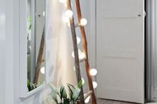 17 a ladder covered with string lights can be used for hanging scarves and bags