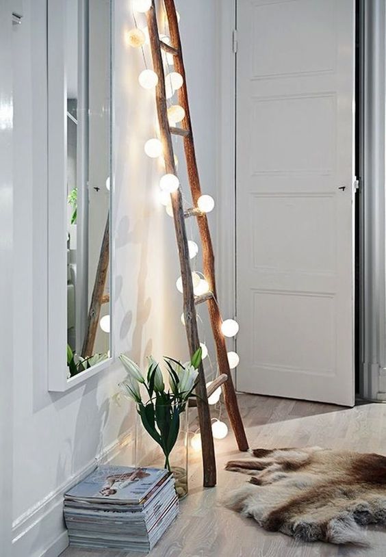 a ladder covered with string lights can be used for hanging scarves and bags