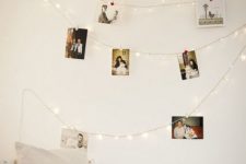 17 string lights with photos hanging on them over the bed