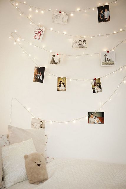 string lights with photos hanging on them over the bed