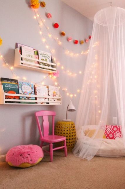a colorful reading nook with a teepee and string lights on the wall