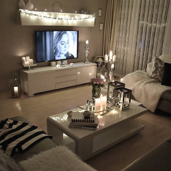 string lights on a shelf over the TV make an accent on this zone and candles add romance