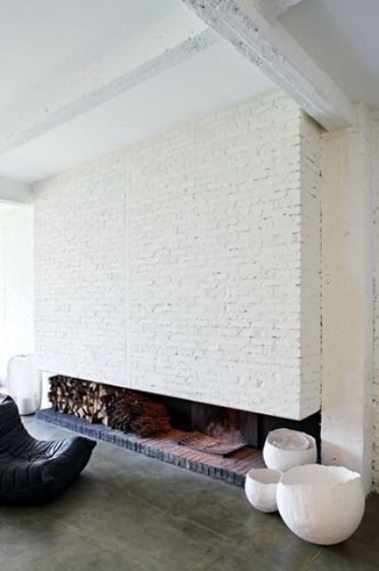 a whole fireplace wall clad with white brick with firewood storage and a hearth