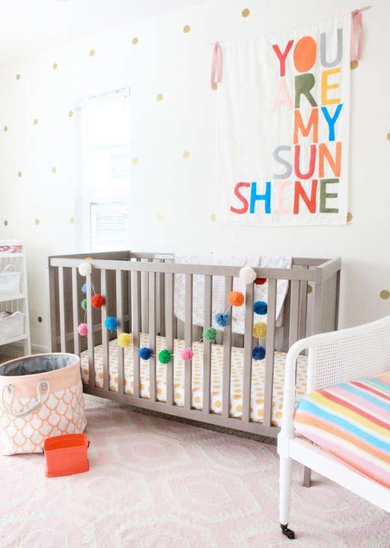 add touches of color to your gender neutral nursery with bright upholstery, a colorful pompom garland and a sign