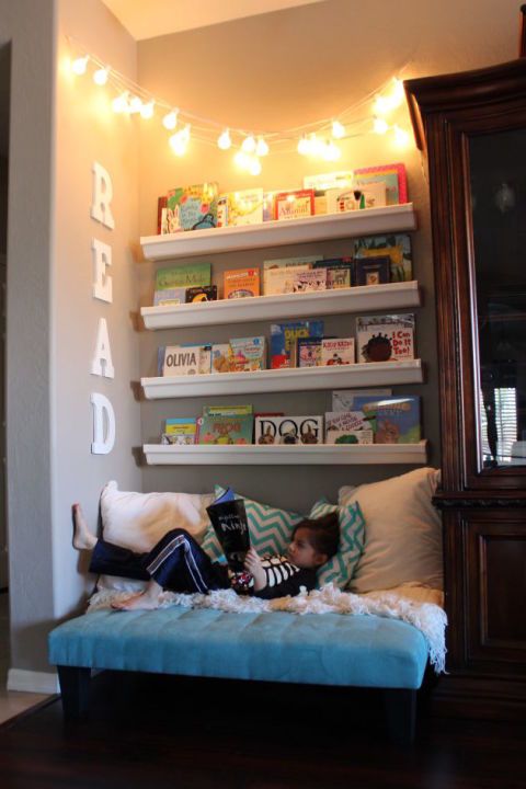 a reading nook with an upholstered bench and shelves plus string lights over it