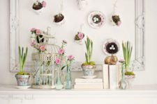 22 a bird cage with blooms, potted bulbs and an artwork with hanging cups with nests inside