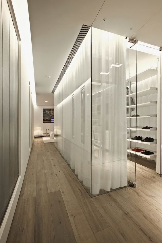 a stylish glass walled closet with lots of open shelves is made more private with curtains
