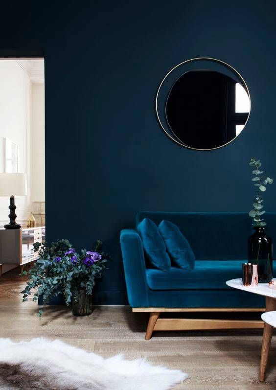 a very chic living room with a velvet sofa that matches the wall color