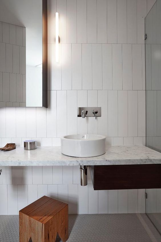 a minimalist bathroom is done with long and narrow white tiles accented with dark grout