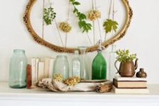 25 an artwork of a vintage oval frame with fresh leaves and blooms and greenery in a pot plus green bottles