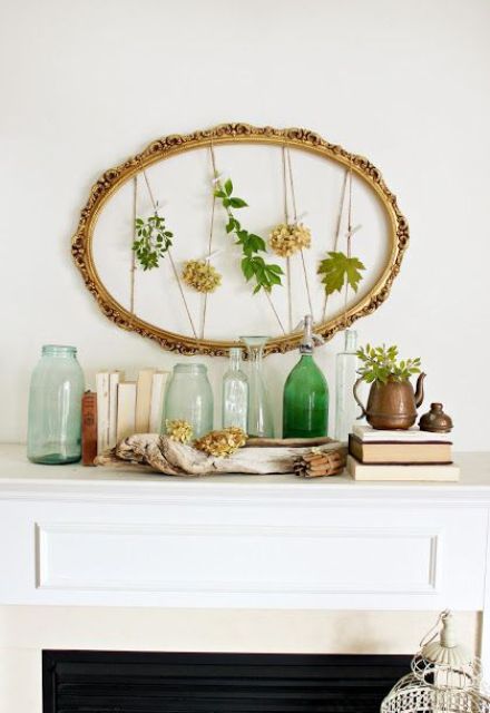 an artwork of a vintage oval frame with fresh leaves and blooms and greenery in a pot plus green bottles