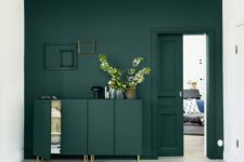 26 a dark green wall and a matching sideboard with brass legs to create a seamless look