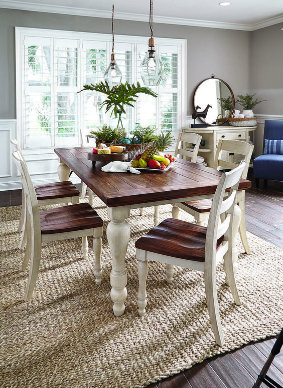 Country cottage-esque white and brown dining room table on a natural fiber rug.