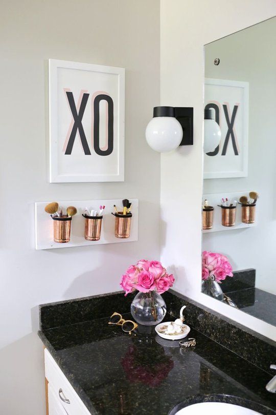 A small wall mounted bathroom organizer with copper jars for makeup stuff