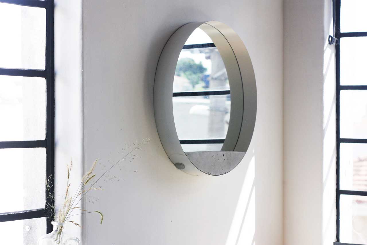 This sleek modern mirror is made of concrete, a metal loop and mirror for a modern or industrial space