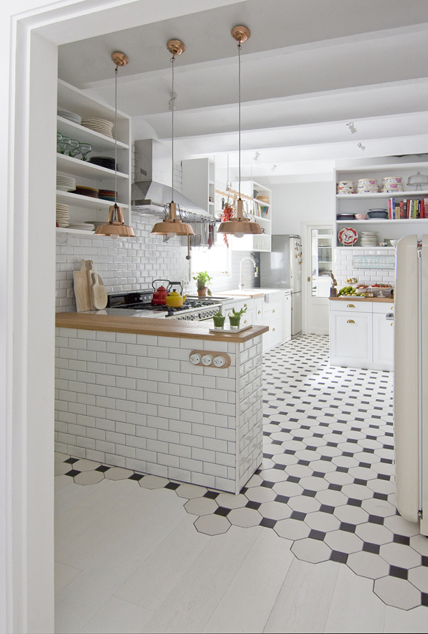 The kitchen features black and white floor and white subway tiles plus wooden touches