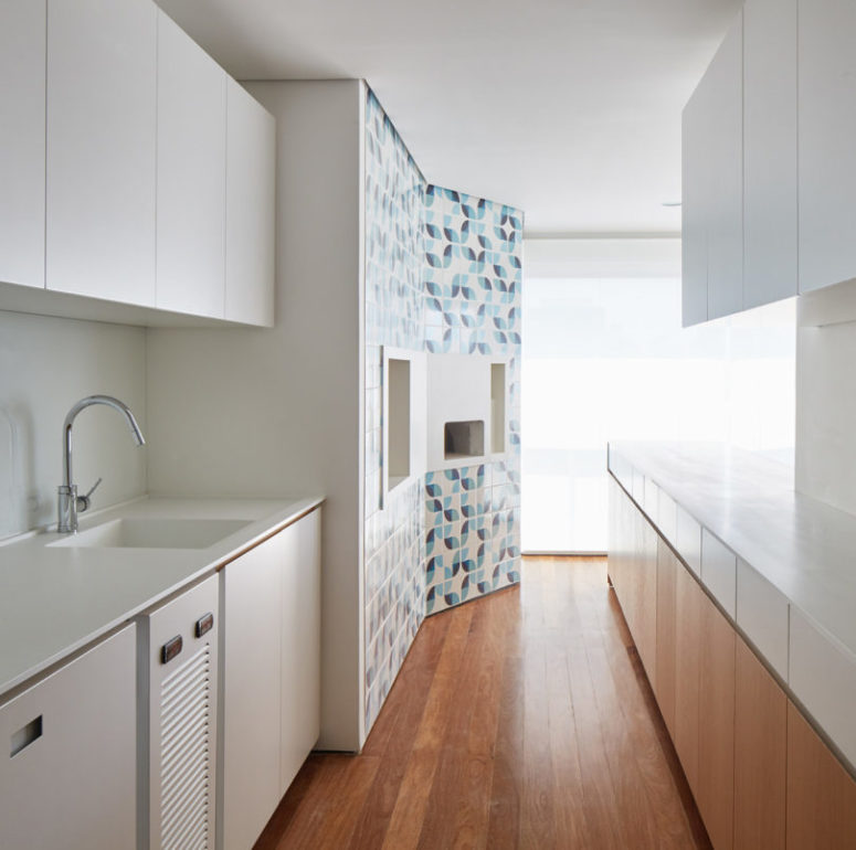 The kitchen is done with white and light-colored wooden cabinets and looks clean and sleek