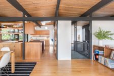 02 The main space is an open layout that comprises a kitchen, a dining room and a living space, it’s clad with light-colored wood and there are dark exposed beams