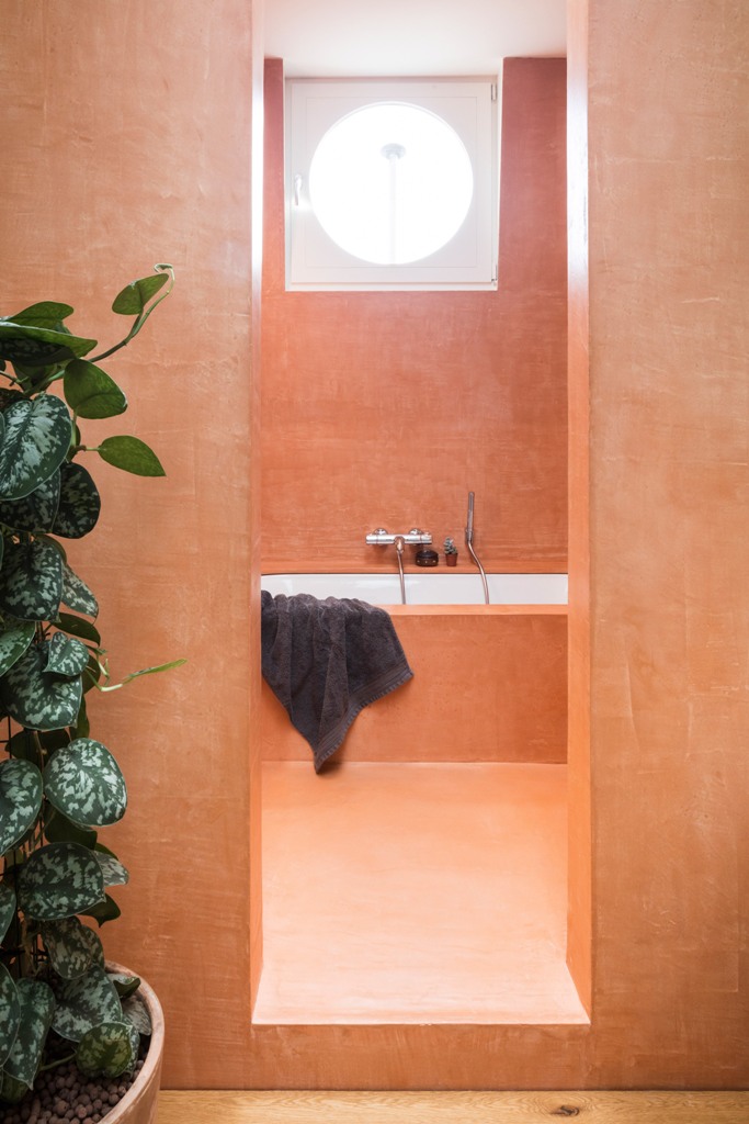 The spaces are done with raw materials for a texture, this bathroom is done in orange for a cheerful feel