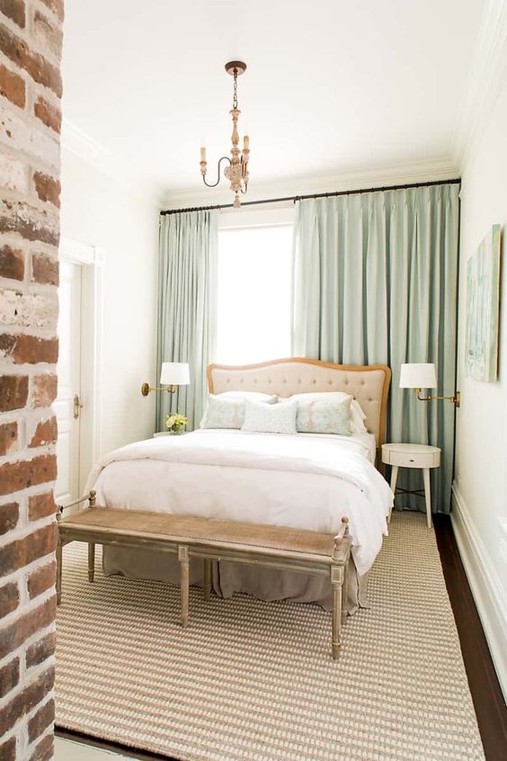 a cozy and sophisticated bedroom with a bed placed against the window and with an exposed brick wall