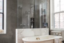 02 a gorgeous marble pony wall with a glass top to organize a space and separate the shower and the bathtub space