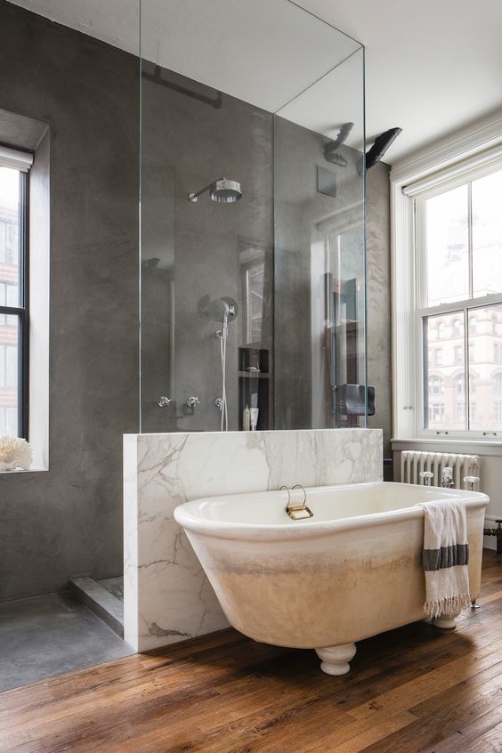 a gorgeous marble pony wall with a glass top to organize a space and separate the shower and the bathtub space