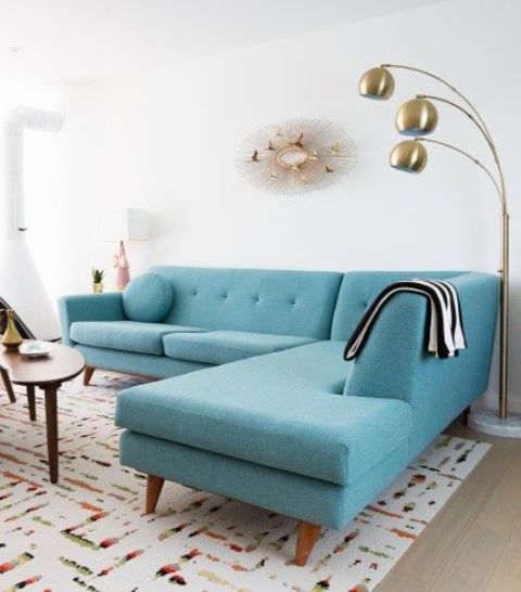 a large turquoise sectional sofa takes a half of this tiny space but it doesn't look small
