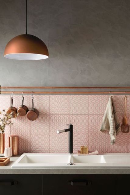 a pink tile backsplash is accented with copper railings and some kitchen stuff on them