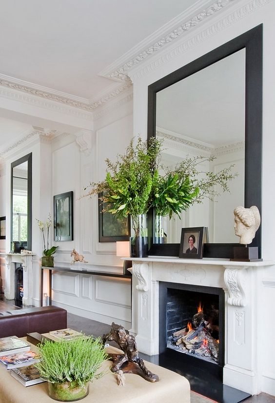 molding on the walls, ceiling and fireplace is combined with a modern mirror and furniture for a harmonious look