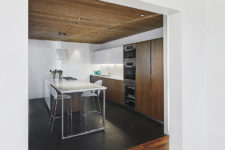 03 The kitchen is done with dark plywood and white sleek surfaces to make it contrasting and bold