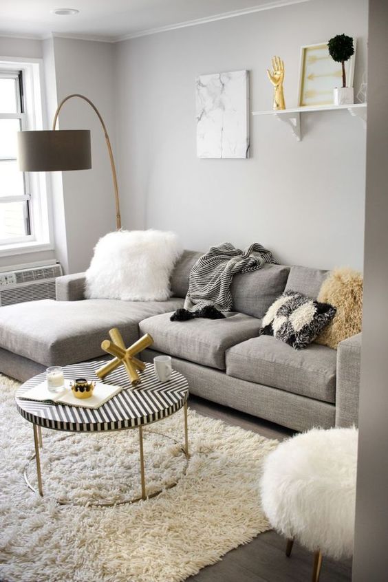 a comfy grey, creamy and gold living room with a large grey sectional sofa that takes half a space