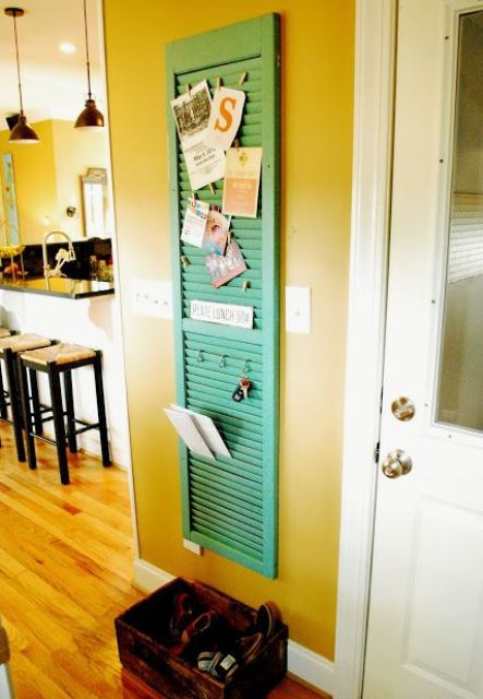a green painted shutter works as a pinboard and a key holder in the entryway