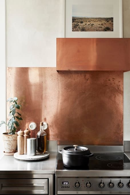 a polished copper sheet backsplash and a matching hood to make the kitchen bolder and cooler
