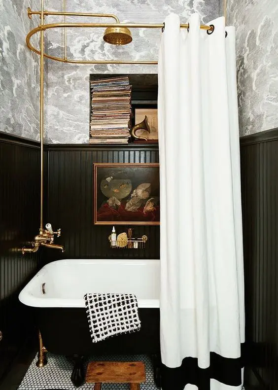 A vintage bathroom with a free standing bathtub and black wainscoting that saves the walls form water