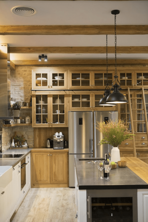 The kitchen island includes a wine cooler, and the lamps are industrial ones